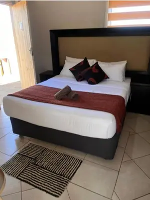 a bedroom with a large bed with two slippers on it at Begin Guesthouse in Ermelo