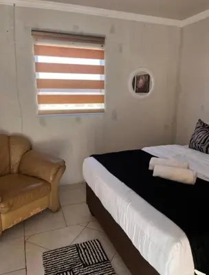 a bedroom with a bed and a couch and a window at Begin Guesthouse in Ermelo