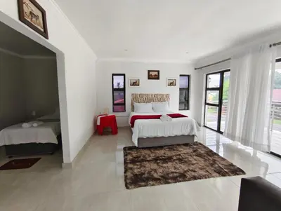 a white bedroom with two beds and a rug at Masingita Guest House in Graskop