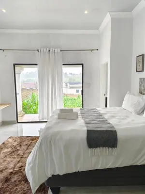 a white bedroom with a large bed and a window at Masingita Guest House in Graskop