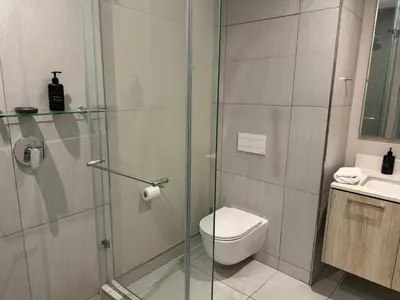 a bathroom with a shower and a toilet and a sink at Modern holiday home in Pretoria