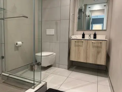 a bathroom with a toilet and a glass shower at Modern holiday home in Pretoria