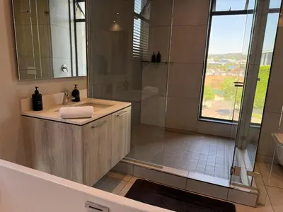 a bathroom with a shower and a sink and a tub at Modern holiday home in Pretoria