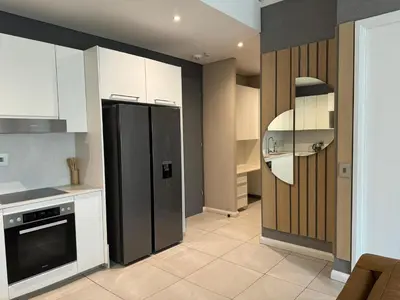 a kitchen with a black refrigerator and white cabinets at Modern holiday home in Pretoria