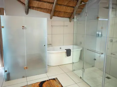 a bathroom with a tub and a glass shower at Highveld Splendour Boutique Bed and Breakfast in Ermelo
