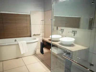 a bathroom with a tub and a sink and a bath tub at Highveld Splendour Boutique Bed and Breakfast in Ermelo
