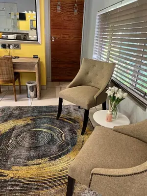 a living room with a chair and a table at Highveld Splendour Boutique Bed and Breakfast in Ermelo