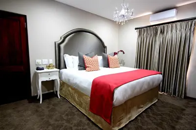 a bedroom with a large bed with a red blanket at La Villa Spa in Nelspruit