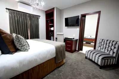 a bedroom with a bed and a chair and a television at La Villa Spa in Nelspruit
