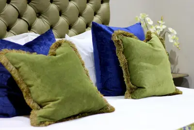 a bed with blue and green pillows on it at La Villa Spa in Nelspruit
