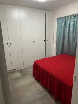 a bedroom with a red bed and white cabinets at AM'S place in Kempton Park