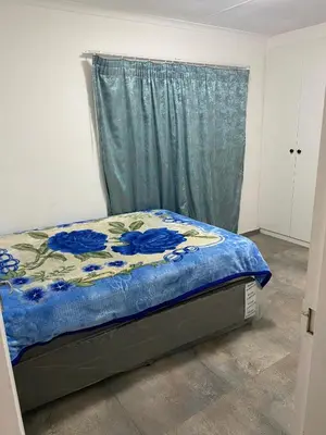 a bedroom with a bed with a blue comforter at AM'S place in Kempton Park