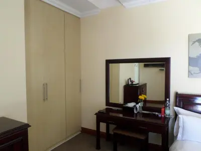 a bedroom with a desk with a mirror and a bed at The Links Guest House in Pretoria