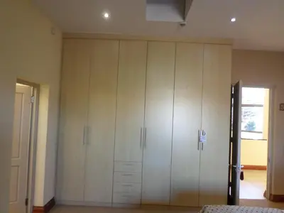 a large closet with white cabinets in a bedroom at The Links Guest House in Pretoria