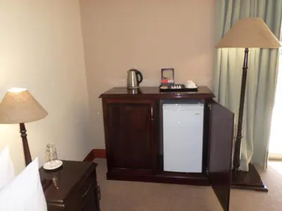 a room with a tv and two lamps in a hotel room at The Links Guest House in Pretoria