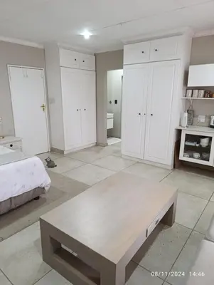 a white bedroom with a bed and a coffee table at Studio S Class and Comfort in Pretoria