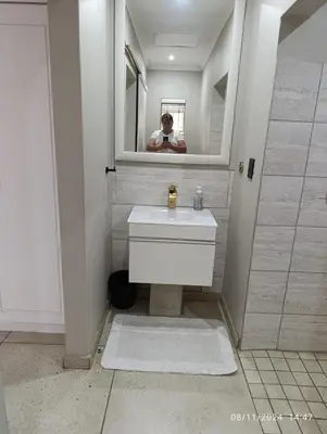a man taking a picture of a bathroom with a sink at Studio S Class and Comfort in Pretoria