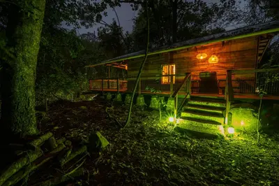 a log cabin in the woods at night at Matumi Trail Forest Lodges - Matumi and Mitzeeri in Tzaneen