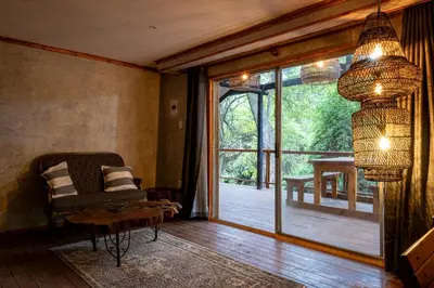 a living room with a chair and a sliding glass door at Matumi Trail Forest Lodges - Matumi and Mitzeeri in Tzaneen