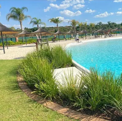 a swimming pool with grass and umbrellas in a resort at Bookings At The Blyde Crystal Lagoon in Pretoria