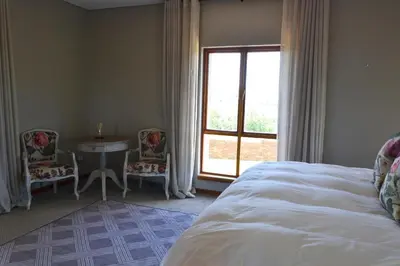 a bedroom with a bed and a table and a window at 22 on Ridgeway in Dullstroom