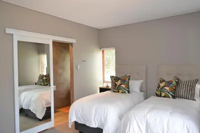 a bedroom with two beds and a mirror at 22 on Ridgeway in Dullstroom