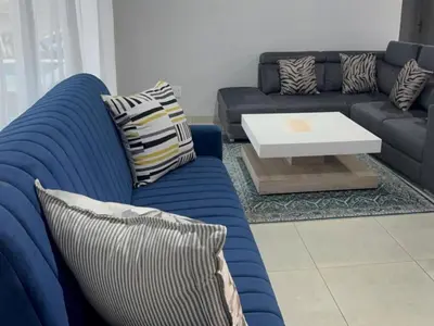 a living room with a blue couch and a table at Royal On Olifant Drive in Marloth Park