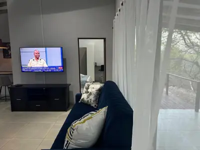 a living room with a blue couch and a tv at Royal On Olifant Drive in Marloth Park