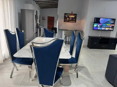 a dining room with blue chairs and a table at Royal On Olifant Drive in Marloth Park