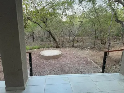 a patio with a bench in the middle of a field at Royal On Olifant Drive in Marloth Park
