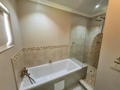 a bathroom with a tub and a glass shower at Spindermolen in Dullstroom