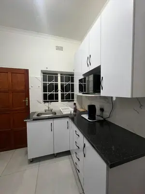 a kitchen with white cabinets and a black counter top at CMK Lodge in Hartbeespoort