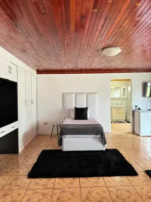 a bedroom with a bed and a wooden ceiling at CMK Lodge in Hartbeespoort