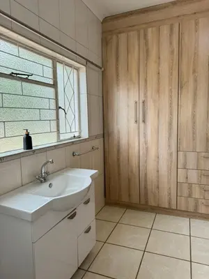 a bathroom with a white sink and wooden cabinets at CMK Lodge in Hartbeespoort