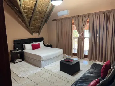 a bedroom with a bed and a couch at VM Guesthouse in Hazyview