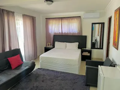 a bedroom with a white bed and a couch at VM Guesthouse in Hazyview