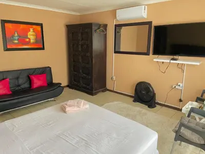 a living room with a couch and a flat screen tv at VM Guesthouse in Hazyview
