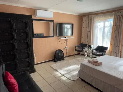 a hotel room with a bed and a tv in it at VM Guesthouse in Hazyview