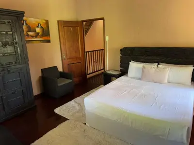 a bedroom with a white bed and a chair at VM Guesthouse in Hazyview