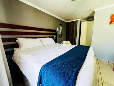 a bedroom with a large white bed with a blue blanket at Dingwako Lodge in Mokopane