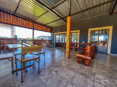 a dining room with a table and chairs and windows at Dingwako Lodge in Mokopane