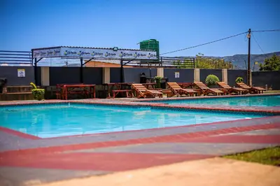 an empty swimming pool with chairs and tables at Dingwako Lodge in Mokopane