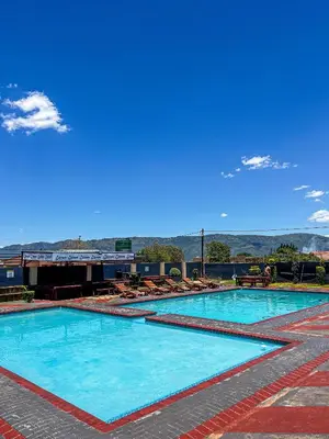 a large swimming pool with blue water and chairs at Dingwako Lodge in Mokopane
