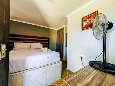 a bedroom with a bed and a fan at Dingwako Lodge in Mokopane