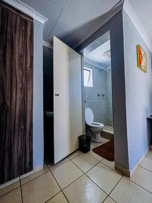 a bathroom with a toilet and a door open at Dingwako Lodge in Mokopane