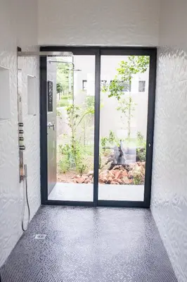 a bathroom with a glass door with a view of a garden at Ziziphus River Lodge in Hectorspruit