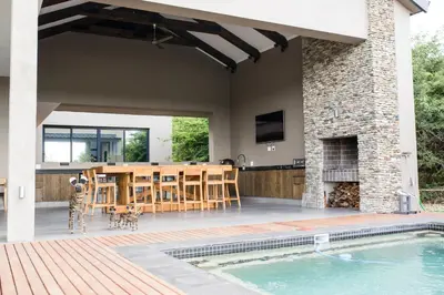 an outdoor patio with a table and a fireplace at Ziziphus River Lodge in Hectorspruit