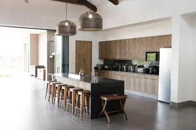 a kitchen with a black counter and some stools at Ziziphus River Lodge in Hectorspruit