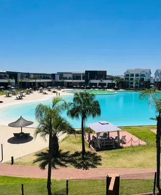 a large swimming pool with palm trees and buildings at The Blyde Paradise Luxury 1 Bed in Pretoria