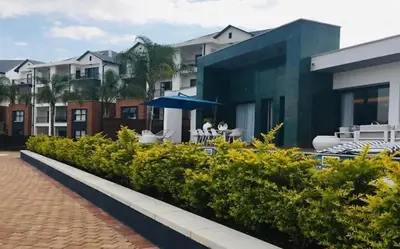 a building with a patio with chairs and an umbrella at The Blyde Paradise Luxury 1 Bed in Pretoria